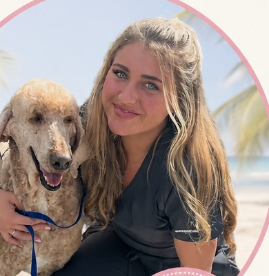 Julia Begany, pet stylist, with a happy groomed poodle on the beach